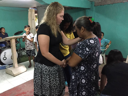 Kaylee Smith prays over a woman at a church.