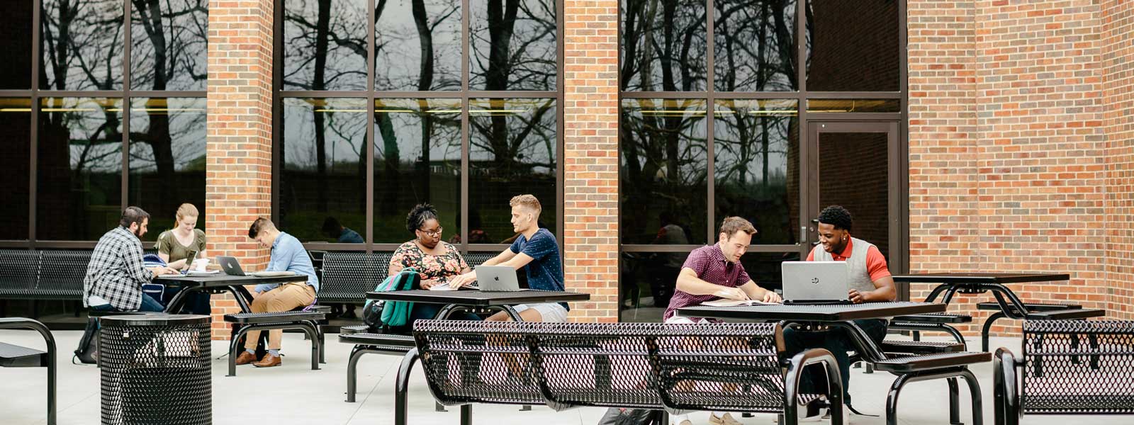 student reading book sitting on floor between library shelves