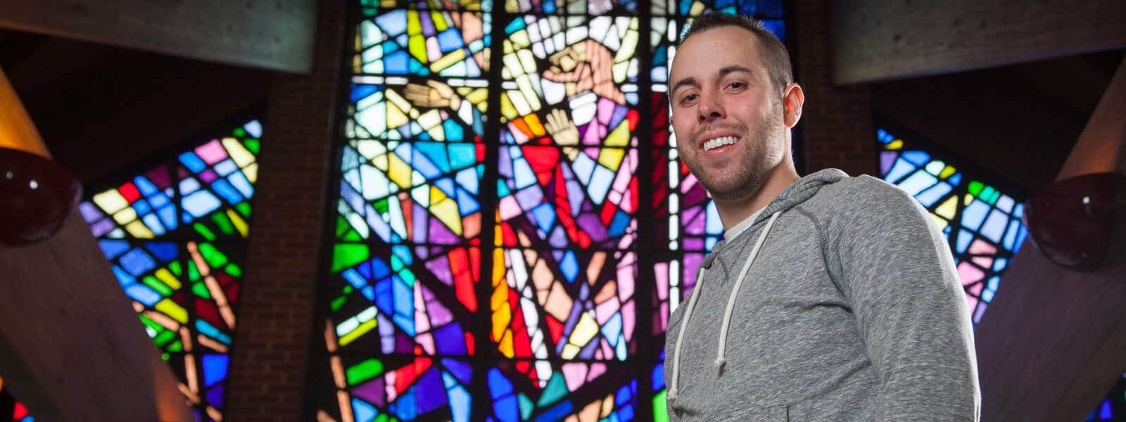 student standing in front of stained glass window in Randolph Chapel