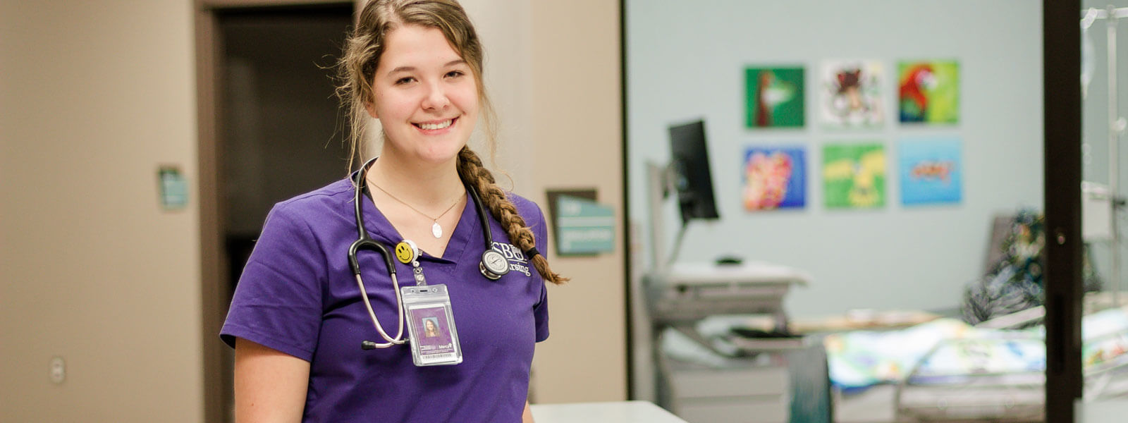 nursing student smiling with simulation lab in background