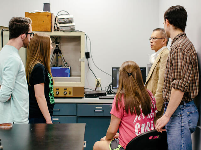 Professor explains chemistry lab equipment to group of students