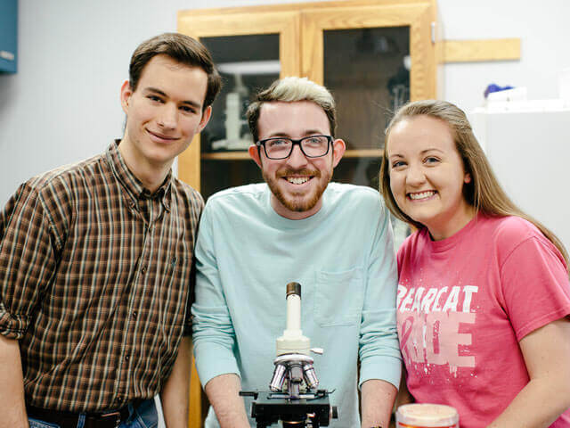 Three students with microscope