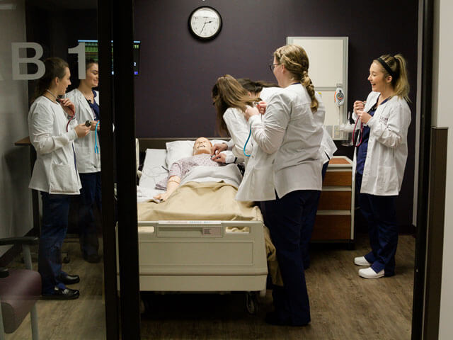 students practice with mannequin in nursing simulation lab
