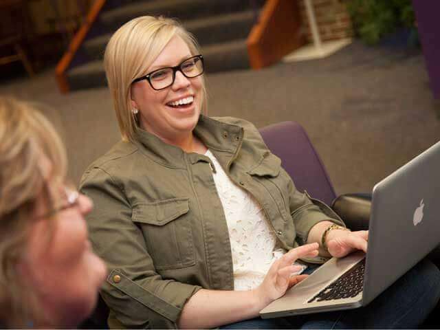 student smiling while holding laptop
